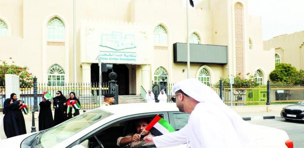 الامارات الان | بلدية دبا الحصن توزع علم الإمارات عـلى منـازل الـمـواطنين والمـقـيمـين | عيون الجزيرة الامارات